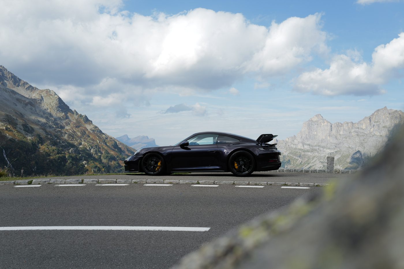 A dark sports car at a mountain viewpoint