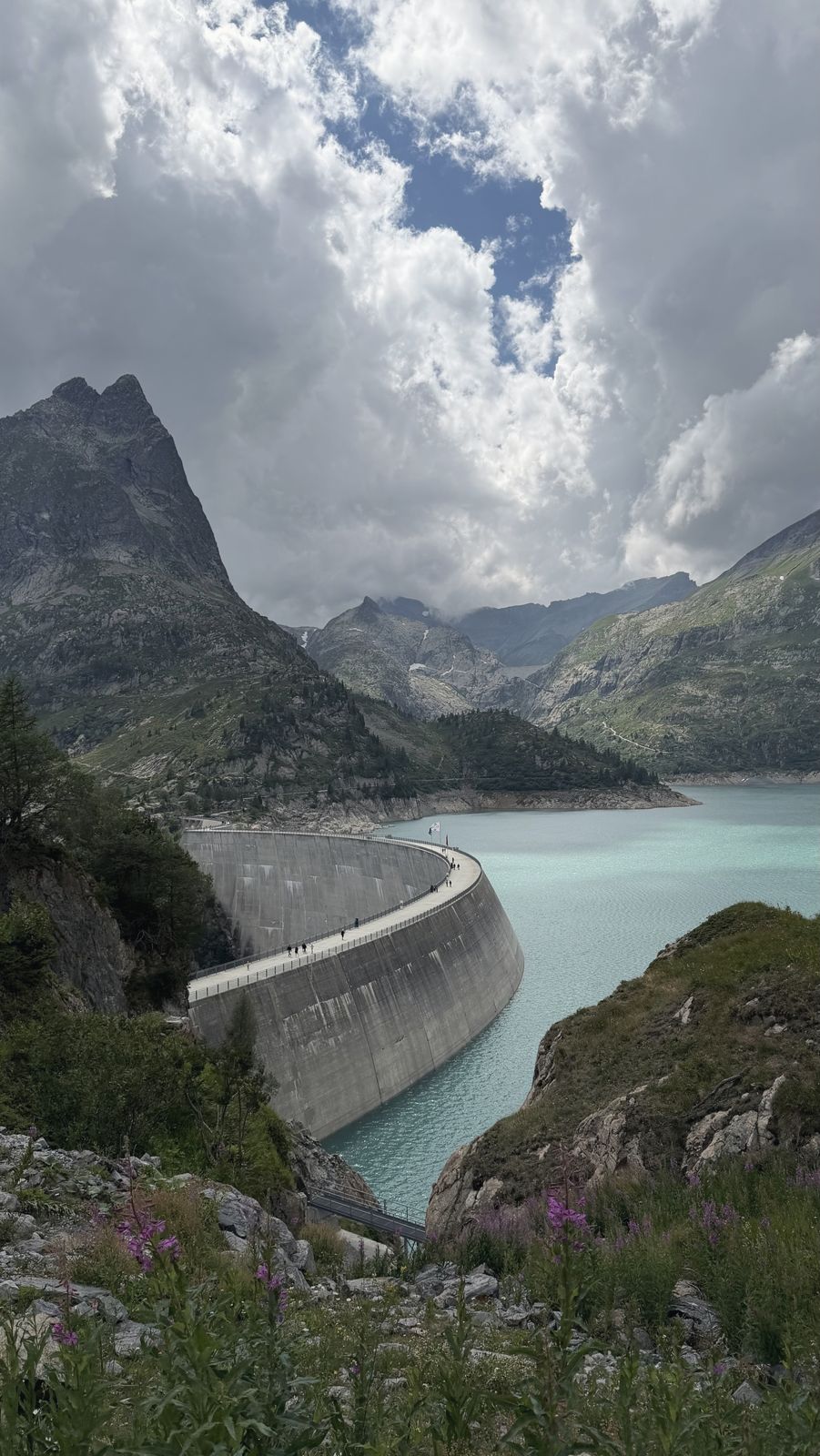 A curved dam above a turquoise lake